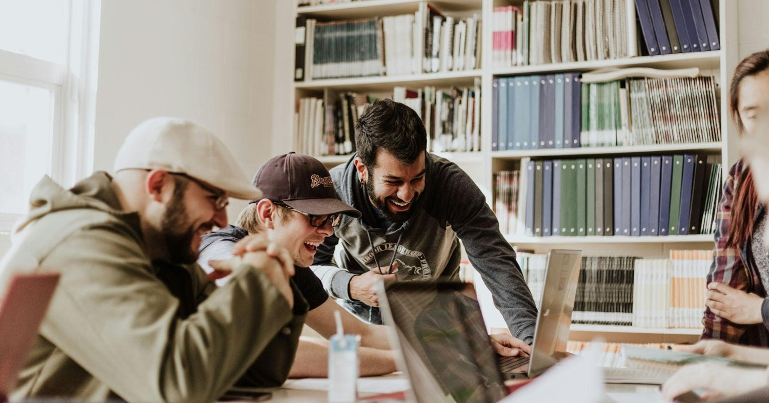 Colleagues smiling while working together on laptops in shared office space