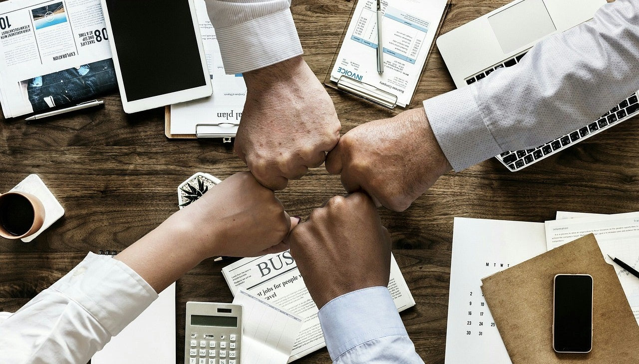 Employees' hands coming together over a workspace